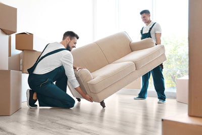 Delivery men moving sofa in room at new home